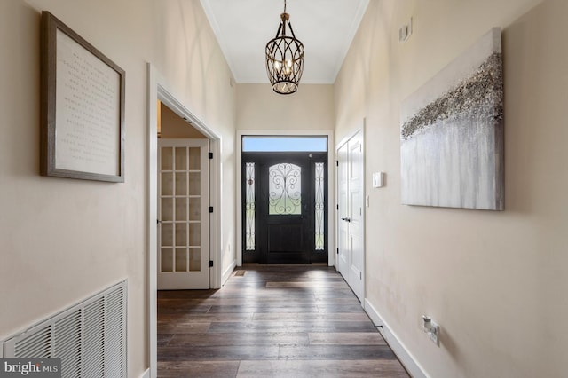 entrance foyer featuring baseboards, a chandelier, wood finished floors, and visible vents