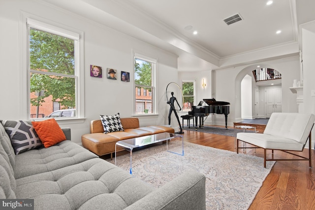living room with visible vents, crown molding, wood finished floors, recessed lighting, and arched walkways