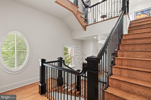 stairs with baseboards, high vaulted ceiling, and wood finished floors