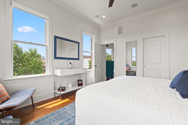 bedroom with wood finished floors, ornamental molding, baseboards, and visible vents