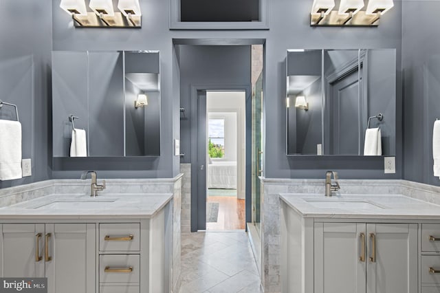 bathroom featuring a sink, a stall shower, and two vanities