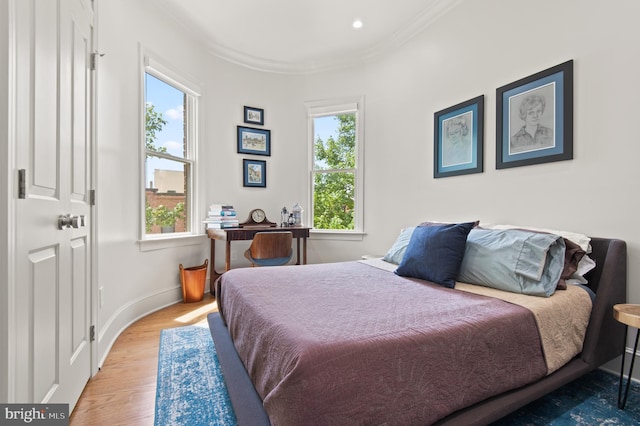 bedroom with baseboards, ornamental molding, wood finished floors, and multiple windows