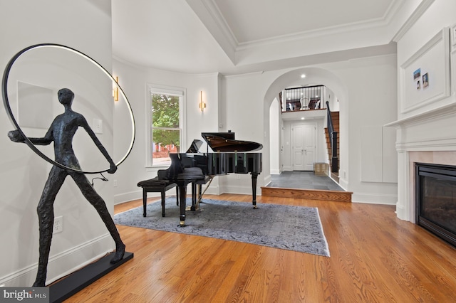 foyer entrance with ornamental molding, baseboards, arched walkways, a tile fireplace, and wood finished floors