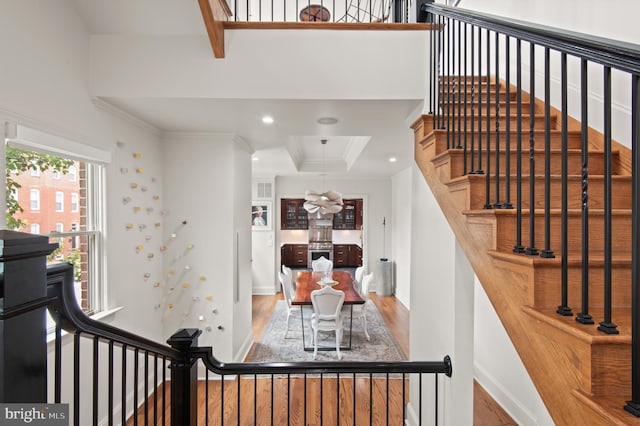 stairway featuring crown molding, wood finished floors, and recessed lighting