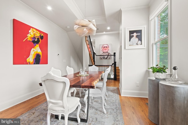 dining area featuring baseboards, crown molding, light wood-style flooring, and stairway