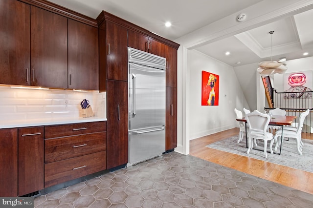 kitchen featuring light countertops, backsplash, built in refrigerator, ornamental molding, and recessed lighting
