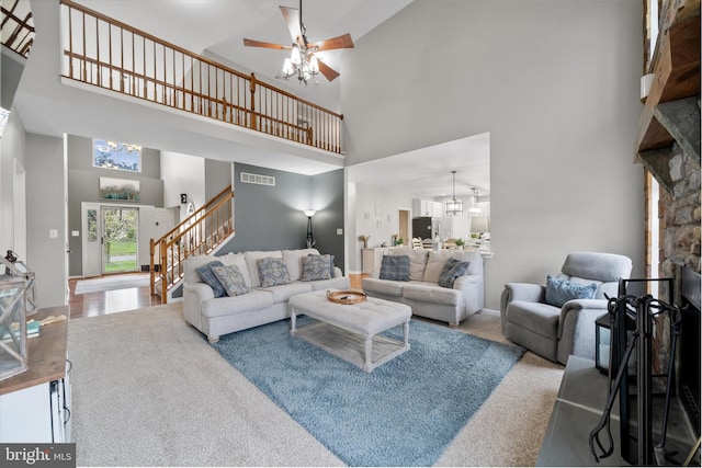 25 Mica St, Townsend, DE 19734 - carpeted living area featuring stairs, a stone fireplace, a high ceiling, and ceiling fan with notable chandelier