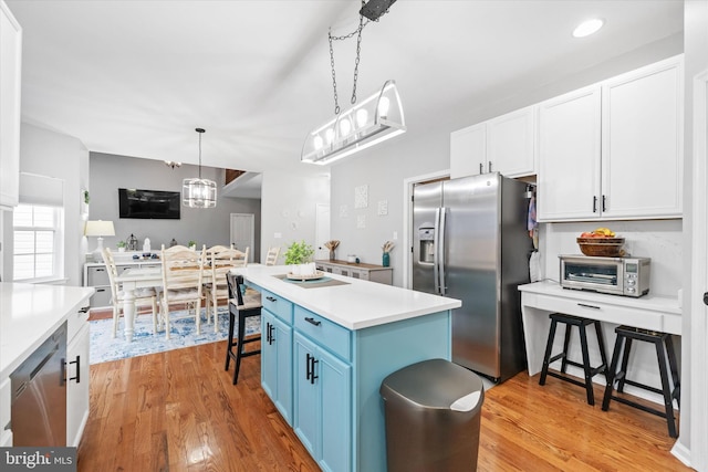25 Mica St, Townsend, DE 19734 - kitchen with decorative light fixtures, light countertops, light wood-style floors, stainless steel appliances, and blue cabinets