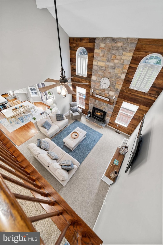 25 Mica St, Townsend, DE 19734 - carpeted living room with high vaulted ceiling, a fireplace, a ceiling fan, visible vents, and wood walls