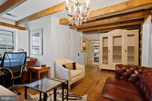 living area with wood-type flooring, a notable chandelier, beam ceiling, and visible vents