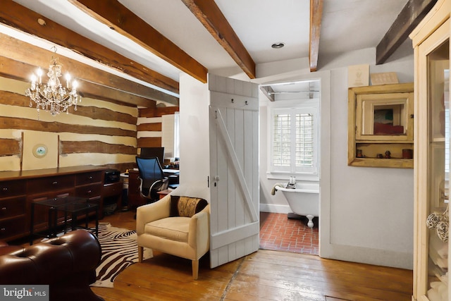 sitting room featuring a chandelier, hardwood / wood-style floors, beam ceiling, and baseboards