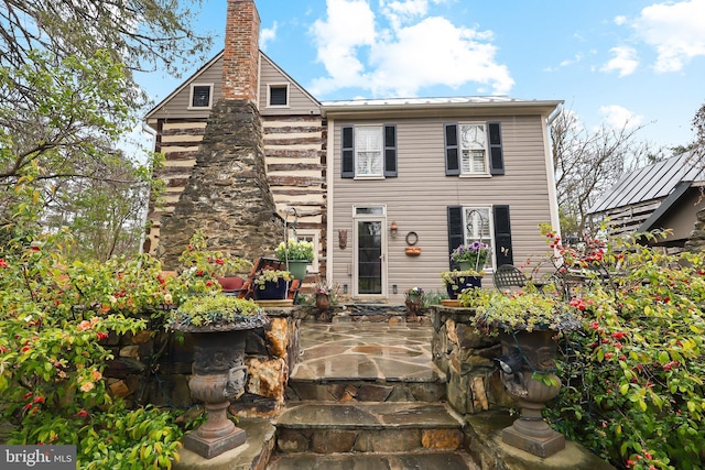 view of front of home featuring log exterior, a patio area, and a chimney
