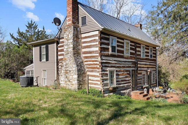 view of side of home with a chimney, log siding, a yard, central air condition unit, and metal roof