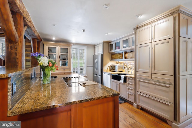 kitchen featuring dark stone counters, recessed lighting, light wood-style floors, glass insert cabinets, and appliances with stainless steel finishes