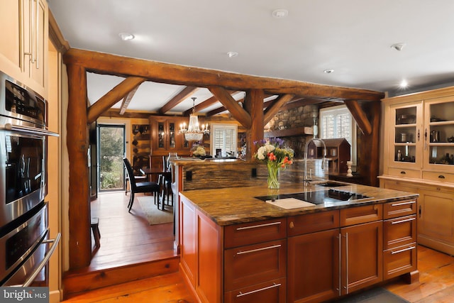 kitchen with hardwood / wood-style flooring, black electric stovetop, oven, and a sink