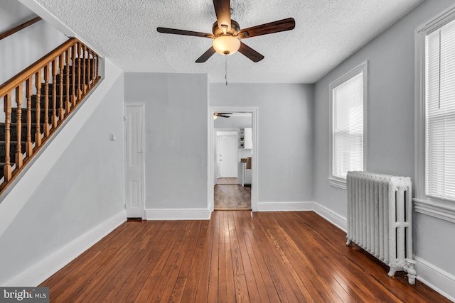 unfurnished living room with baseboards, a ceiling fan, stairs, radiator heating unit, and hardwood / wood-style floors