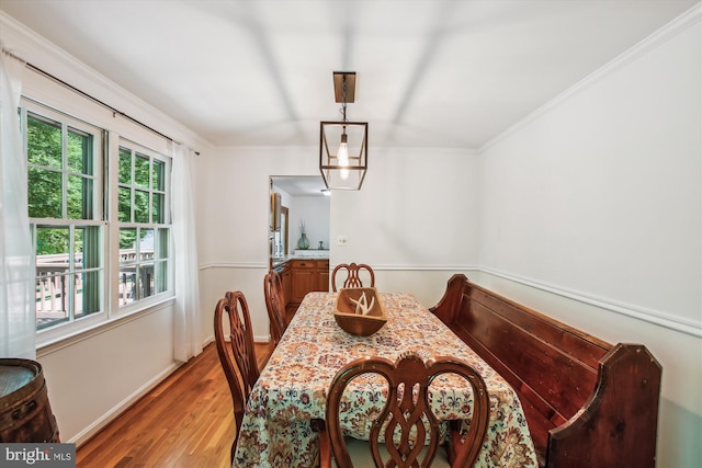 dining room with baseboards, ornamental molding, and light wood finished floors