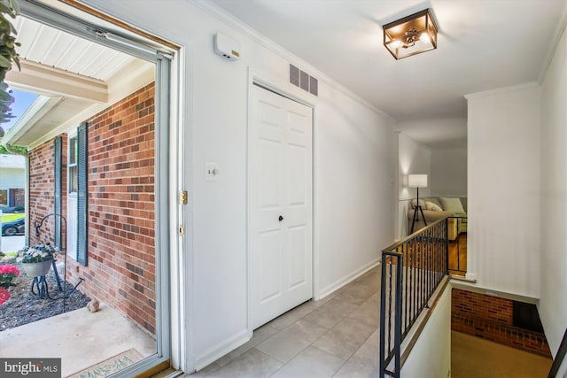 corridor featuring an upstairs landing, ornamental molding, light tile patterned floors, and visible vents