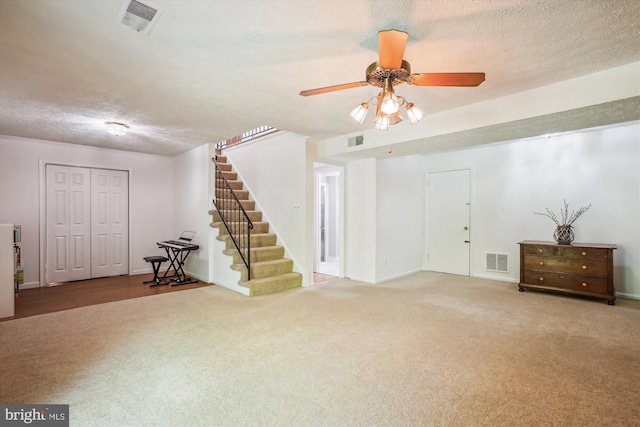 basement with carpet flooring, a textured ceiling, visible vents, and stairway