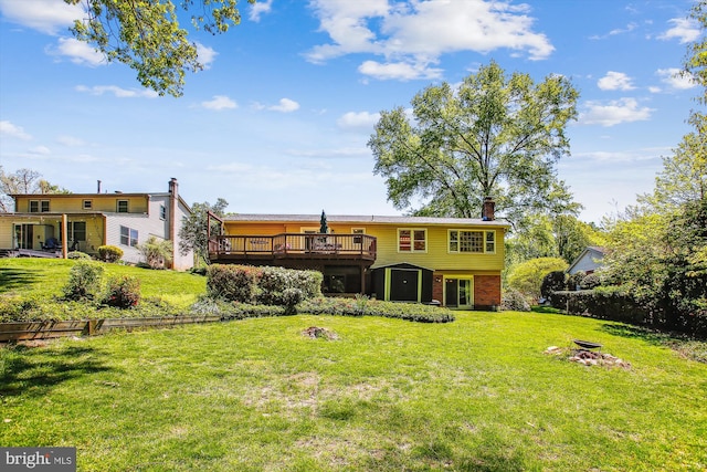 rear view of property with a chimney, brick siding, a yard, and a deck