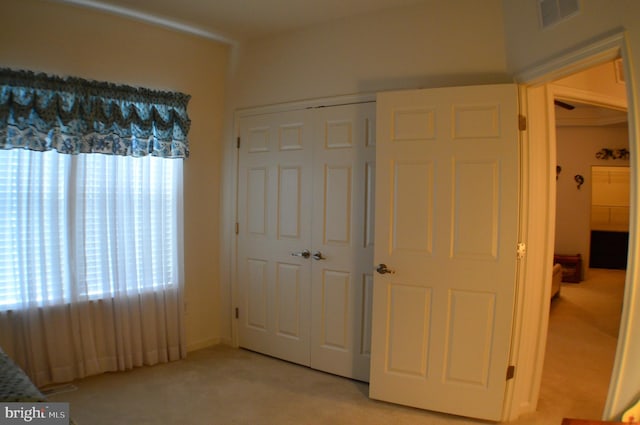 unfurnished bedroom featuring visible vents, a closet, and light carpet