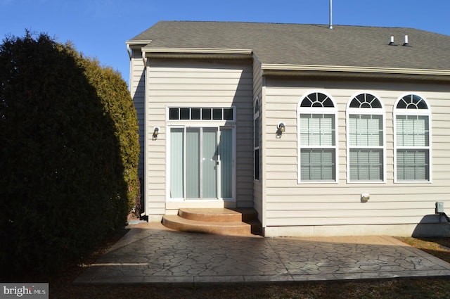 back of property with a shingled roof and a patio area