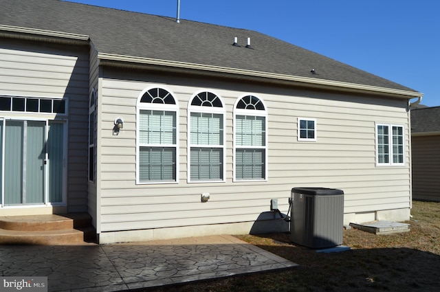 back of house with roof with shingles, a patio area, entry steps, and central AC unit