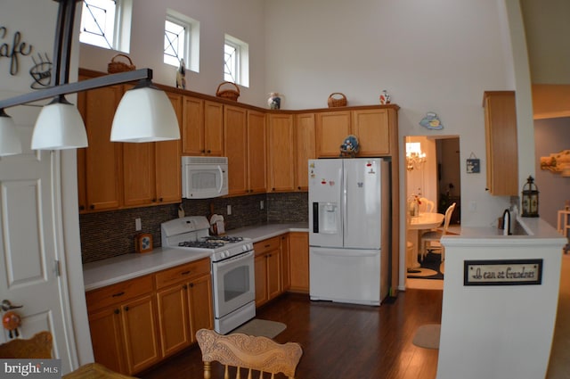 kitchen with tasteful backsplash, dark wood-style flooring, light countertops, white appliances, and a towering ceiling