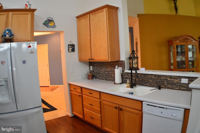 kitchen with tasteful backsplash, white appliances, a sink, and dark wood finished floors