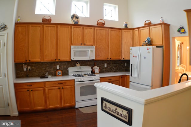 kitchen featuring brown cabinets, decorative backsplash, light countertops, and white appliances