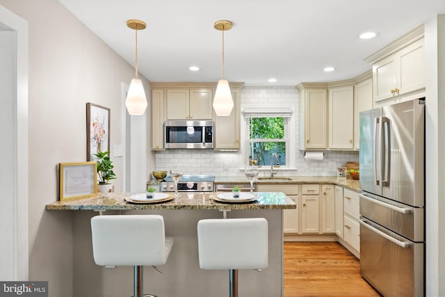 8620 Conover Pl, Alexandria, VA 22308 - kitchen featuring stainless steel appliances, a sink, a peninsula, light stone counters, and tasteful backsplash