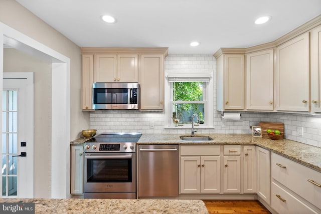 8620 Conover Pl, Alexandria, VA 22308 - kitchen with appliances with stainless steel finishes, a sink, cream cabinetry, backsplash, and light stone countertops