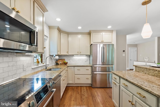 8620 Conover Pl, Alexandria, VA 22308 - kitchen featuring appliances with stainless steel finishes, a sink, light wood-type flooring, backsplash, and cream cabinetry