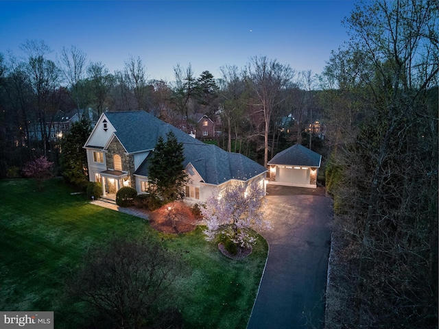 view of front of property featuring stone siding, an outbuilding, a garage, a front lawn, and driveway