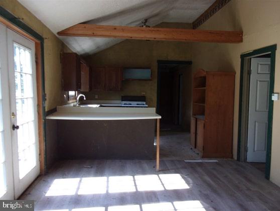 kitchen with vaulted ceiling with beams, light countertops, a wealth of natural light, and light wood-style flooring