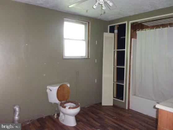 full bath featuring wood finished floors, toilet, ceiling fan, and a shower with curtain