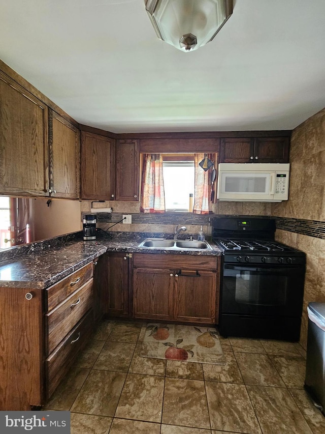 kitchen featuring black gas stove, white microwave, and a sink