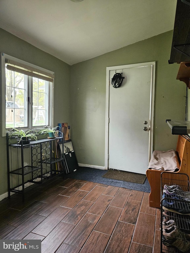 interior space featuring baseboards, lofted ceiling, and wood finish floors