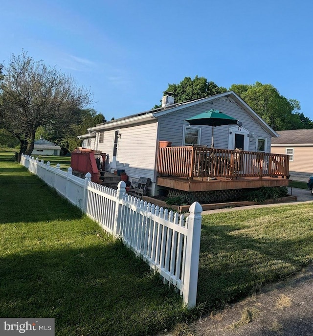 manufactured / mobile home featuring fence, a wooden deck, and a front yard