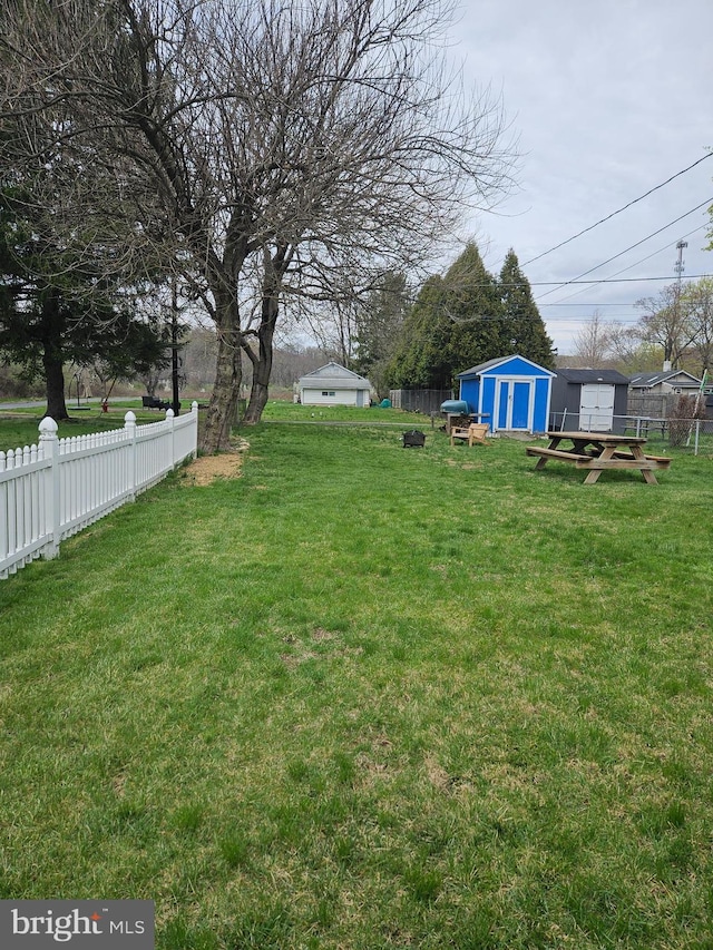 view of yard featuring a storage unit, an outbuilding, and fence