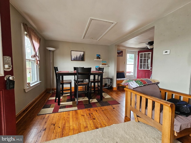 dining space featuring hardwood / wood-style floors, ceiling fan, baseboards, and attic access