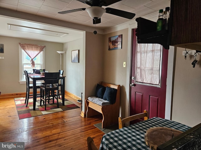 dining space featuring wood-type flooring, a ceiling fan, ornamental molding, and baseboards