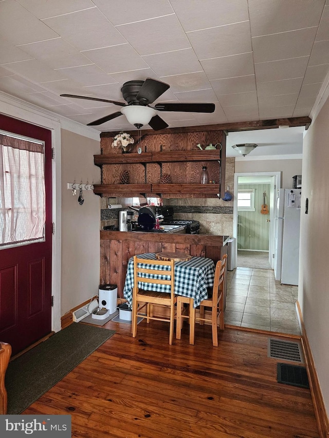 dining area with wood finished floors, visible vents, crown molding, and ceiling fan