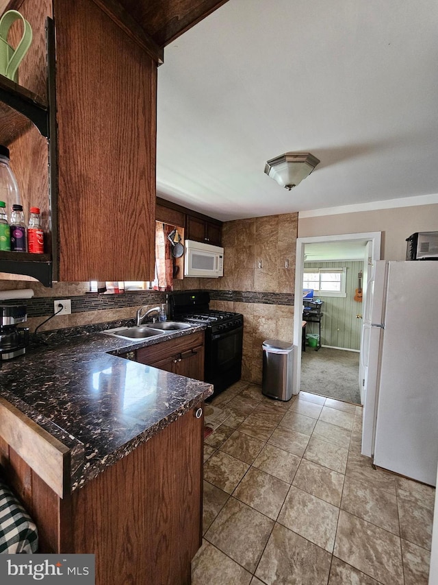 kitchen with a sink, dark countertops, light tile patterned floors, and white appliances
