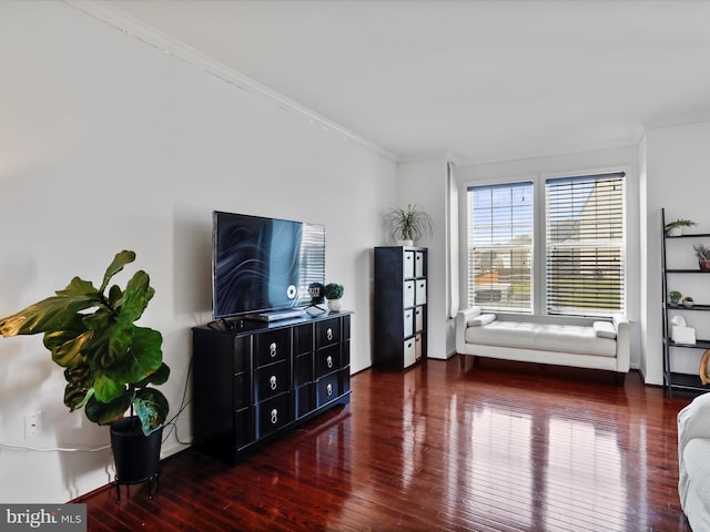 living area featuring baseboards, crown molding, and hardwood / wood-style flooring