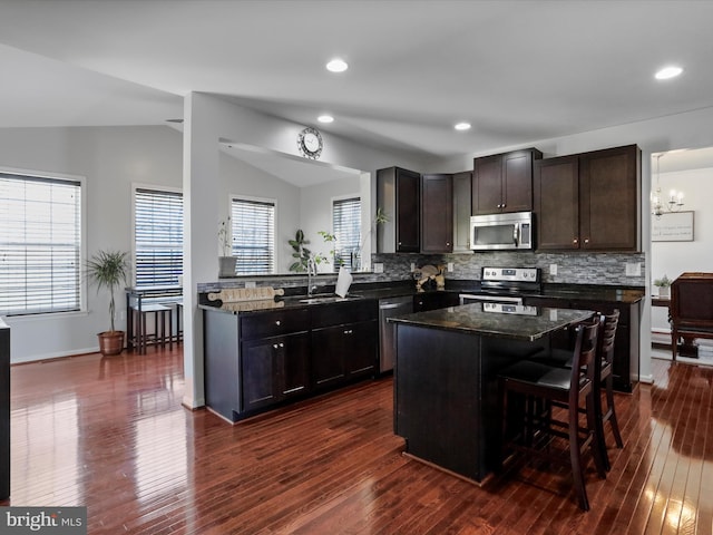 kitchen featuring dark wood finished floors, lofted ceiling, decorative backsplash, and stainless steel appliances