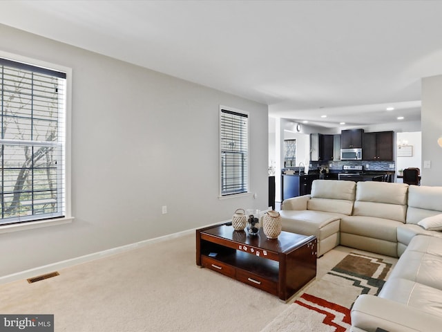 living area with recessed lighting, visible vents, light colored carpet, and a healthy amount of sunlight