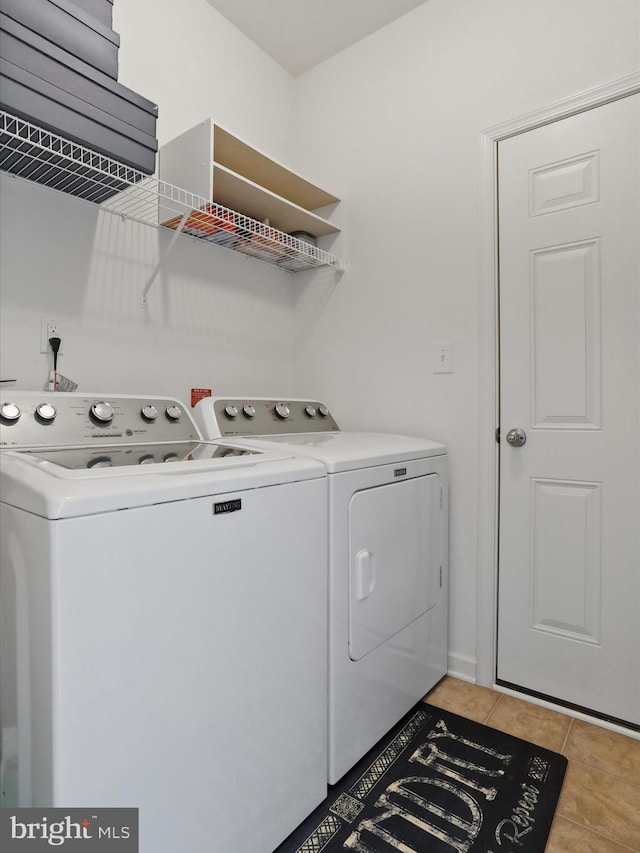 laundry area featuring washer and clothes dryer, laundry area, and light tile patterned flooring