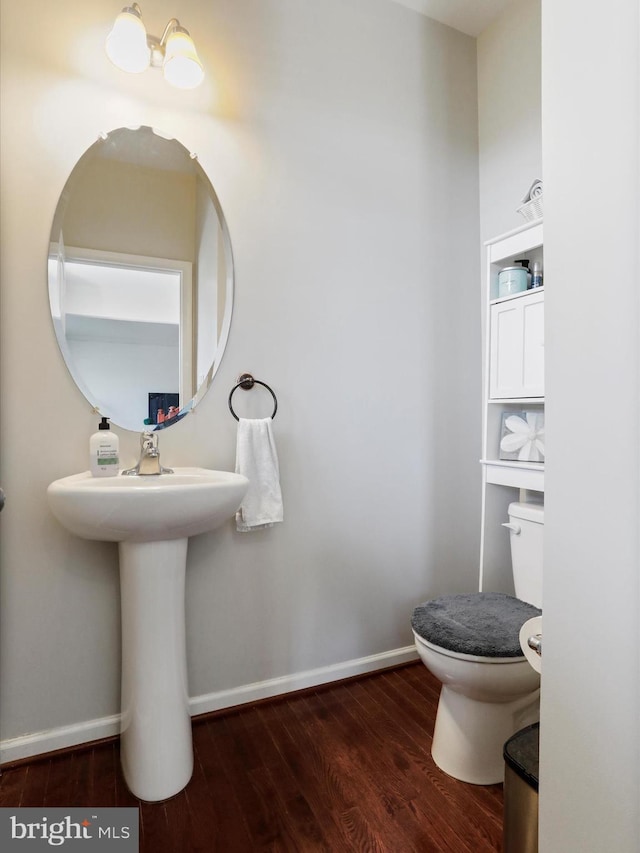 bathroom featuring toilet, wood finished floors, and baseboards