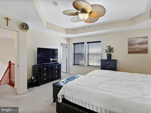 bedroom with a tray ceiling, carpet flooring, and baseboards